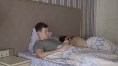 Adam telefon ve çıplak kadın yatakta yatıyordu
