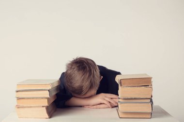 İlköğretim okul çağındaki bir çocuk ev ödevi yap. Çocuk ödevini evde masasında çalışıyor. Öğrenci ders üzerinde sıkılmış oldu. Çocuk ödev sırasında uykuya daldı. Güzel birinci sınıf öğrencisi.