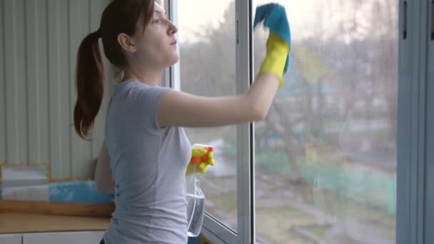 Красивая брюнетка в перчатках моет окна — стоковое видео