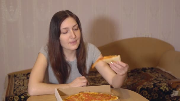 Mujer morena comiendo pizza apetitosa en casa — Vídeo de stock