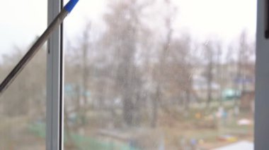 Genç kadın kauçuk paspas ile pencere yıkama