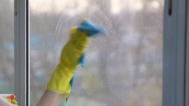 Mavi bir bez ile pencere sarı eldiven kadında yıkıyor