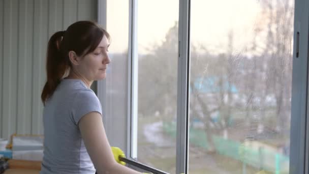 Mujer con guantes amarillos lavando la ventana de una fregona especial — Vídeo de stock