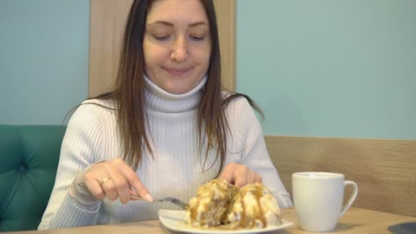 Красивая женщина в кафе пьет кофе с десертом — стоковое видео