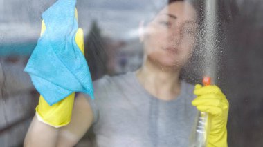 Bir mavi bez ve temizleyici ile pencere güzel kadın yıkar.