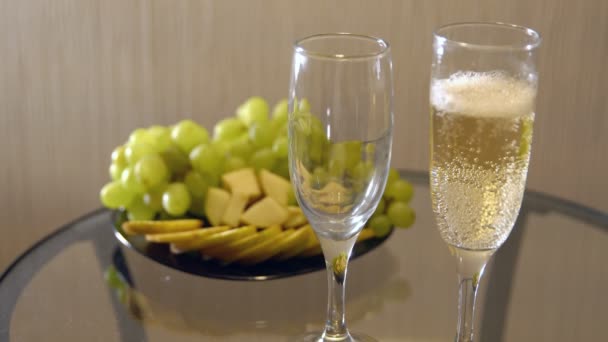 Encontro romântico. Derramando champanhe em copos em uma mesa com fruto — Vídeo de Stock