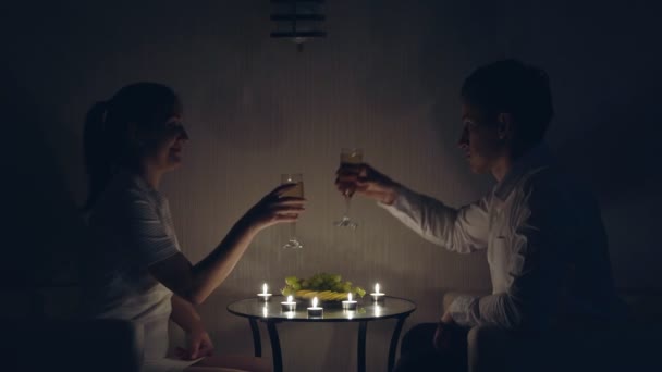 Романтичний вечір свічками. Чоловік і жінка п'ють шампанське — стокове відео