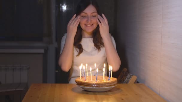 Молодая женщина задувает свечи на праздничном торте — стоковое видео