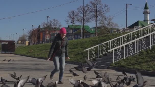 Junge Frau jagt an einem sonnigen Tag Tauben — Stockvideo