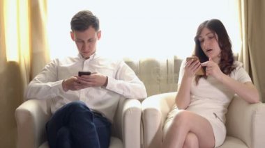 Genç adam ve kadın telefonların koltuklar ile
