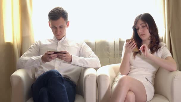 Jonge man en vrouw met telefoons in Fauteuils — Stockvideo