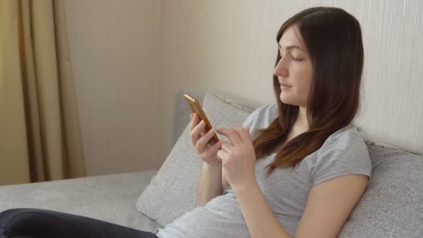 Jonge vrouw zittend op de Bank met telefoon — Stockvideo