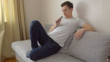 Genç adam bir telefon ile kanepede oturuyor