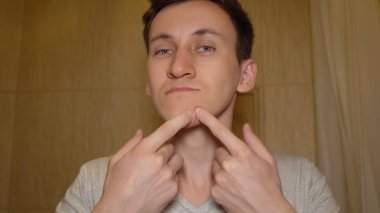 Genç adam onun yüzünde sivilce sıkmak için çalışır.