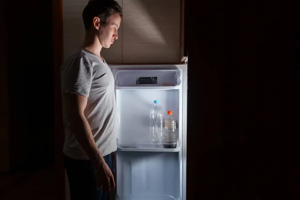 Молодой Человек Ест Ночью Возле Холодильника — стоковое фото