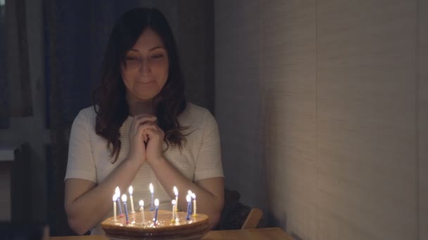 Mulher bonita soprando velas em um bolo festivo — Vídeo de Stock