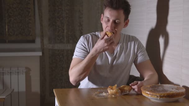 Hombre en la cocina comiendo un bollo por la noche — Vídeo de stock