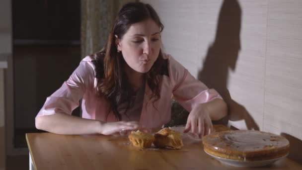 Jonge vrouw nachts in de keuken het eten van een broodje — Stockvideo