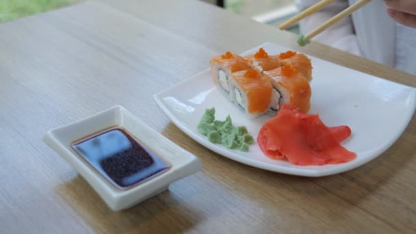 Close-up of rolls with salmon. A womans hand rolls rolls into soy sauce — Stock Video