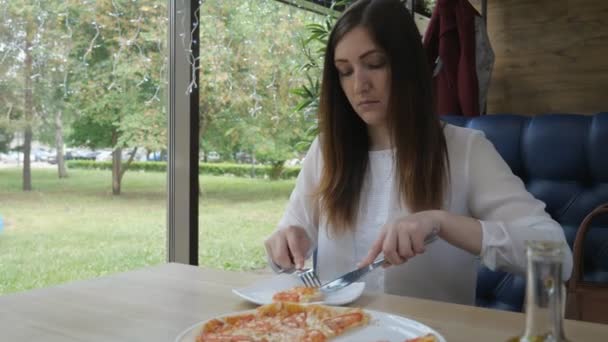 Bruneta žena jíst pizzu v kavárně. Rychlé a nezdravé stravy — Stock video