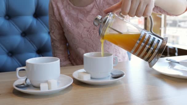 Mujer joven vierte té de frutas en tazas en un café — Vídeo de stock