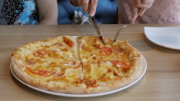 Женщины в кафе выкладывают ломтики пиццы на тарелки — стоковое видео
