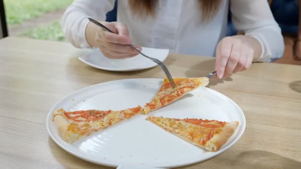 Pizzaria. Jovem leva uma fatia de pizza em seu prato — Vídeo de Stock