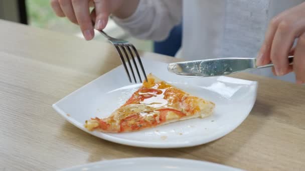 Порізати шматочок піци ножем і виделкою на білій тарілці — стокове відео