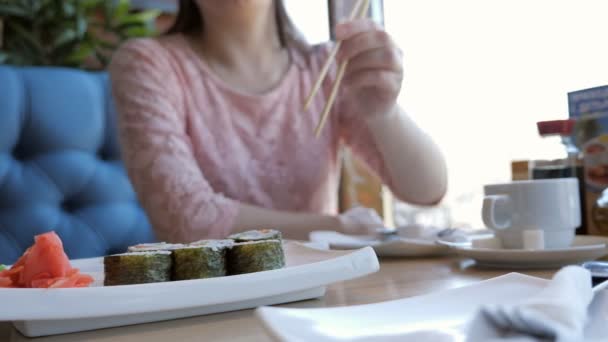 Молодая женщина обедает в кафе, ест роллы — стоковое видео