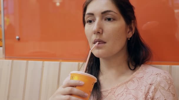 Женщина из кафе пьет сок, поедая его в кафе. — стоковое видео