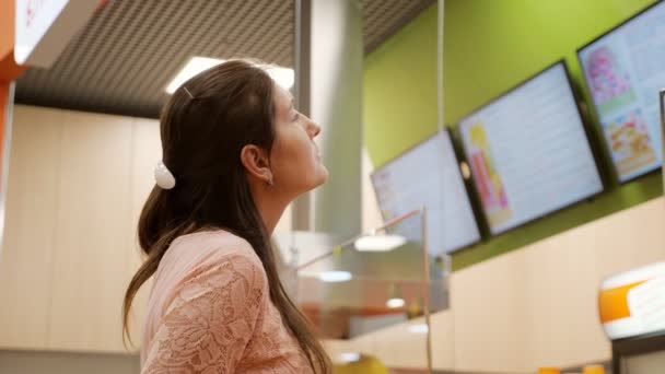 Jeune fille attrayante acheteur choisit menu dans le café — Video