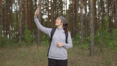 Ormanda cep telefonu sinyalini yakalamaya çalışan genç bir kadın.