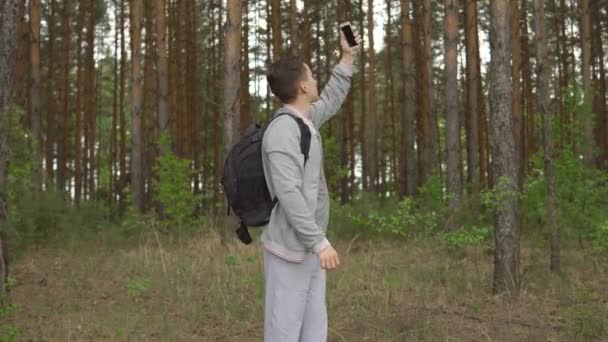 Jovem na floresta tentando pegar um sinal móvel — Vídeo de Stock