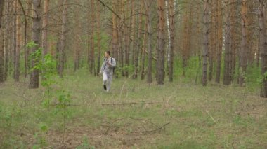 bir sırt çantası ile genç adam ormanda yürür. Önden görünüm