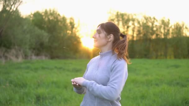 Brünette Frau turnt bei Sonnenaufgang auf dem Feld — Stockvideo