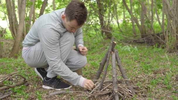 Joven está encendiendo un fuego en el bosque — Vídeos de Stock