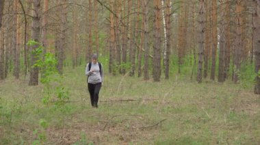 kadın bir sırt çantası ile ormanda yürür. Önden görünüm