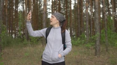 Ormanda cep telefonu sinyalini yakalamaya çalışan genç bir kadın.