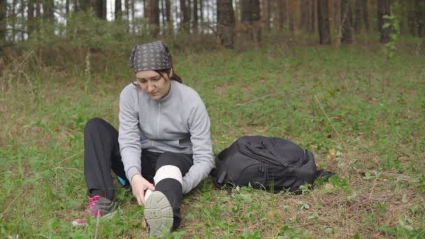 Молода жінка надає першу допомогу після травми себе в лісі — стокове відео