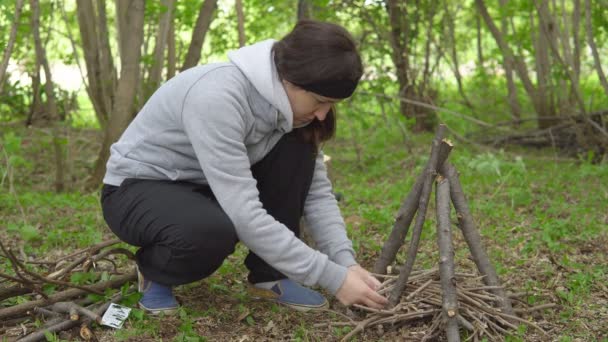 Bruneta žena zapaluje oheň v lese — Stock video