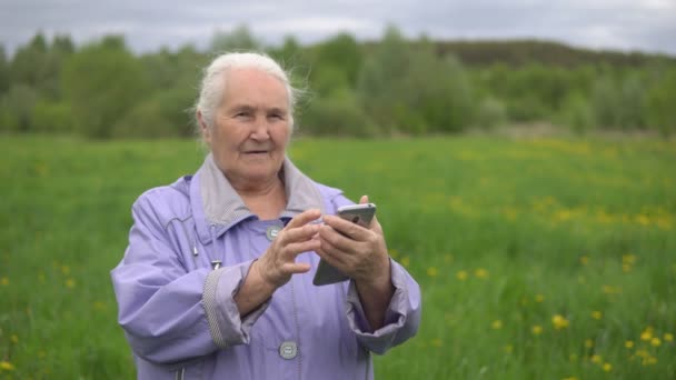 Mujer adulta con el pelo gris en el campo lanza una cinta en el teléfono — Vídeos de Stock