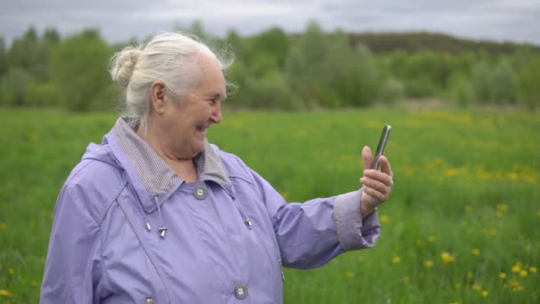 Adult woman with gray hair laughs, looking at the phone — Stock Video