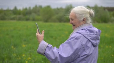 gri saçlı yetişkin kadın gülüyor, seyir telefon