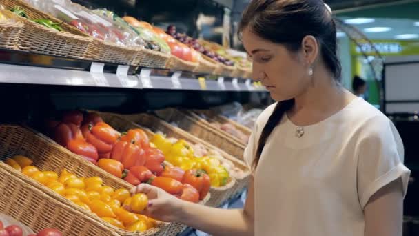 Mujer joven en la tienda de comestibles elige verduras — Vídeo de stock