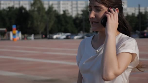 Donna bruna per strada sta lasciando cadere un telefono mentre parla — Video Stock