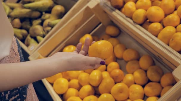 Mujer joven en la tienda de comestibles elige fruta — Vídeos de Stock