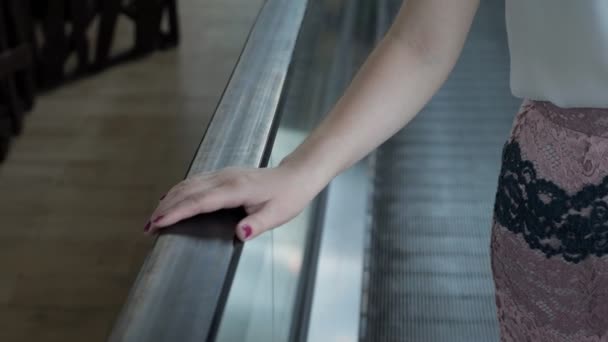 Γυναίκα βόλτες σε μια κυλιόμενη σκάλα που κατέχουν πάνω στο κιγκλίδωμα — Αρχείο Βίντεο