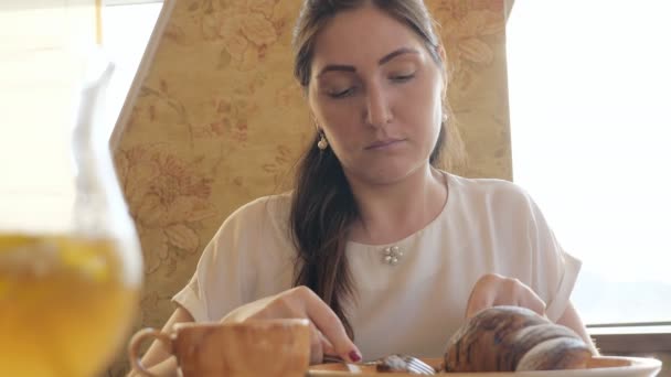 Mulher bonita na mesa comendo um croissant — Vídeo de Stock