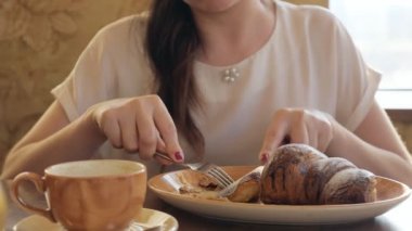 esmer kadın bir kruvasan ve kahve şarkı bir kafede yemek