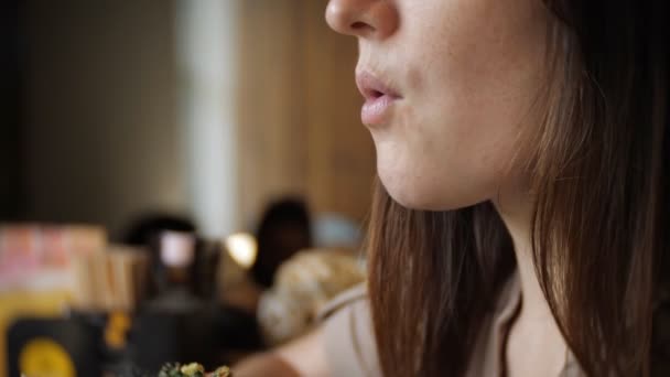 Крупным планом неизвестной девушки в черных перчатках, поедающей бургер в кафе — стоковое видео